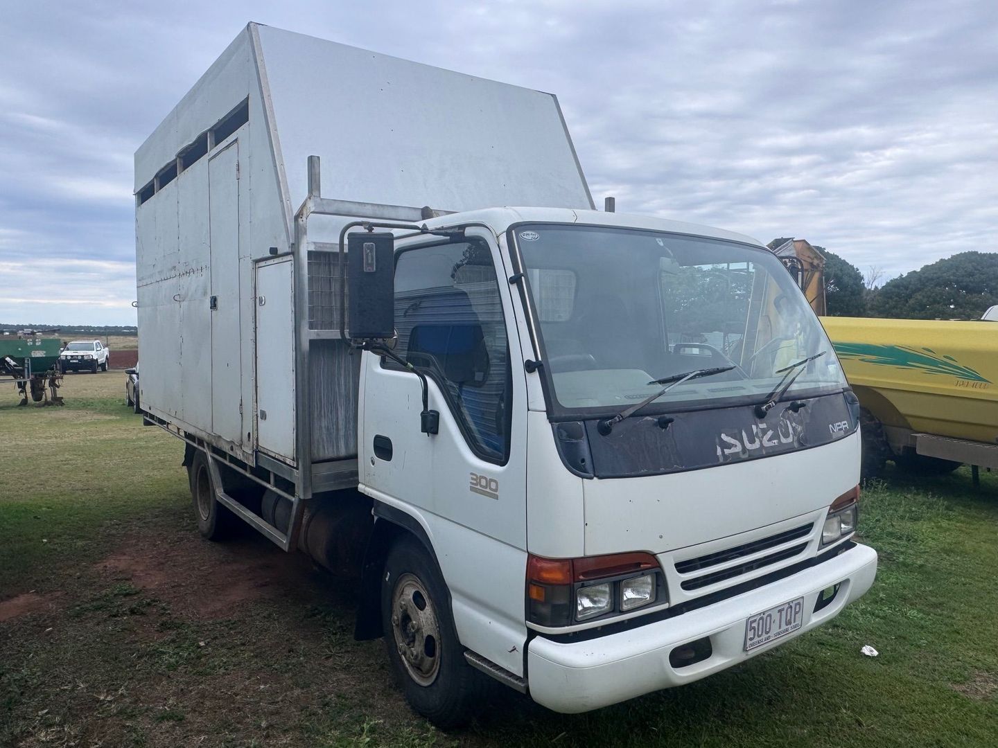 White Isuzu Truck with A Large Box Body Parked on Grass — Bundaberg Auction Centre in Gooburrum, QLD