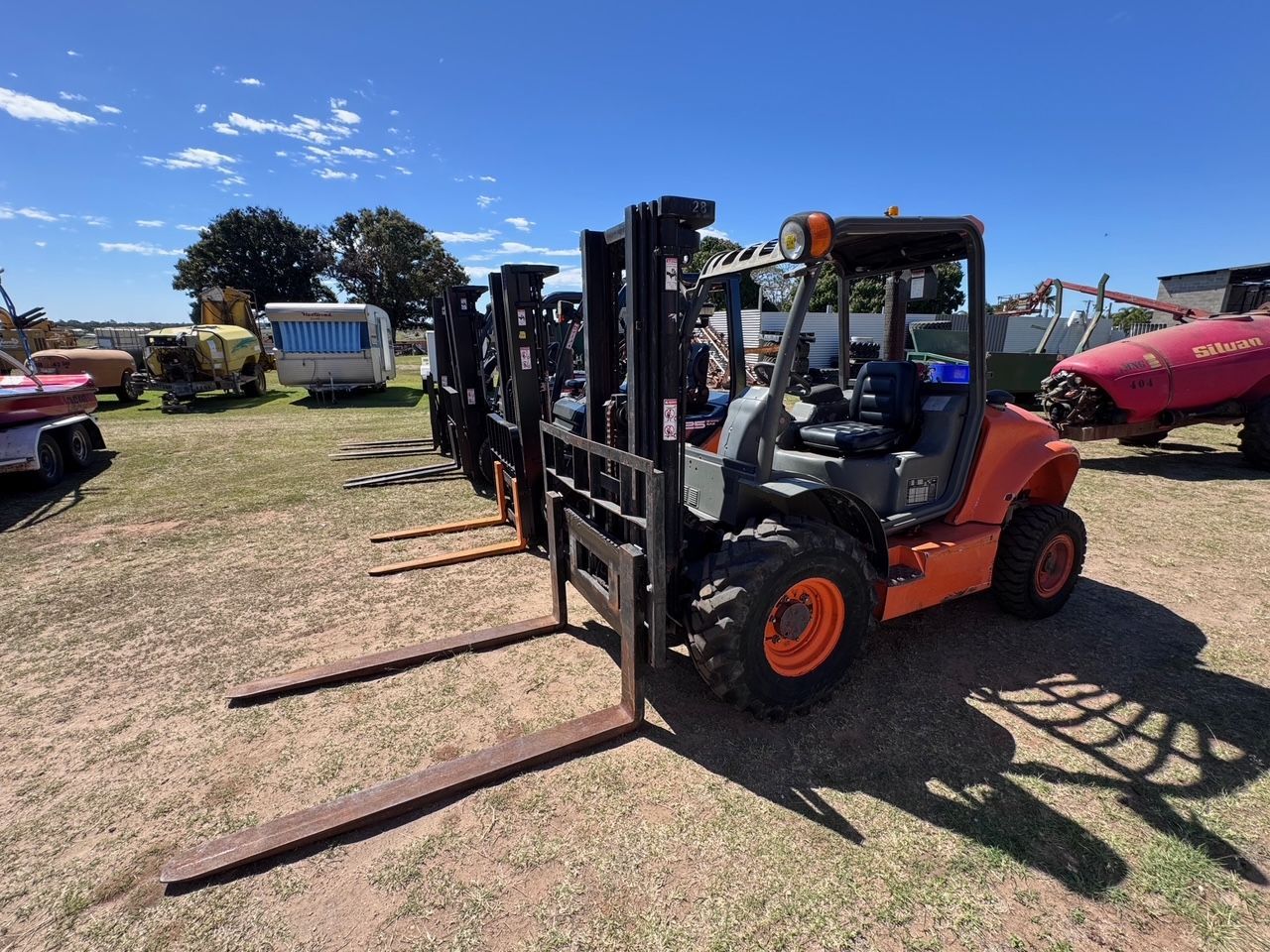 Orange Forklift with Large Tires Parked on A Grassy Field — Bundaberg Auction Centre in Gooburrum, QLD