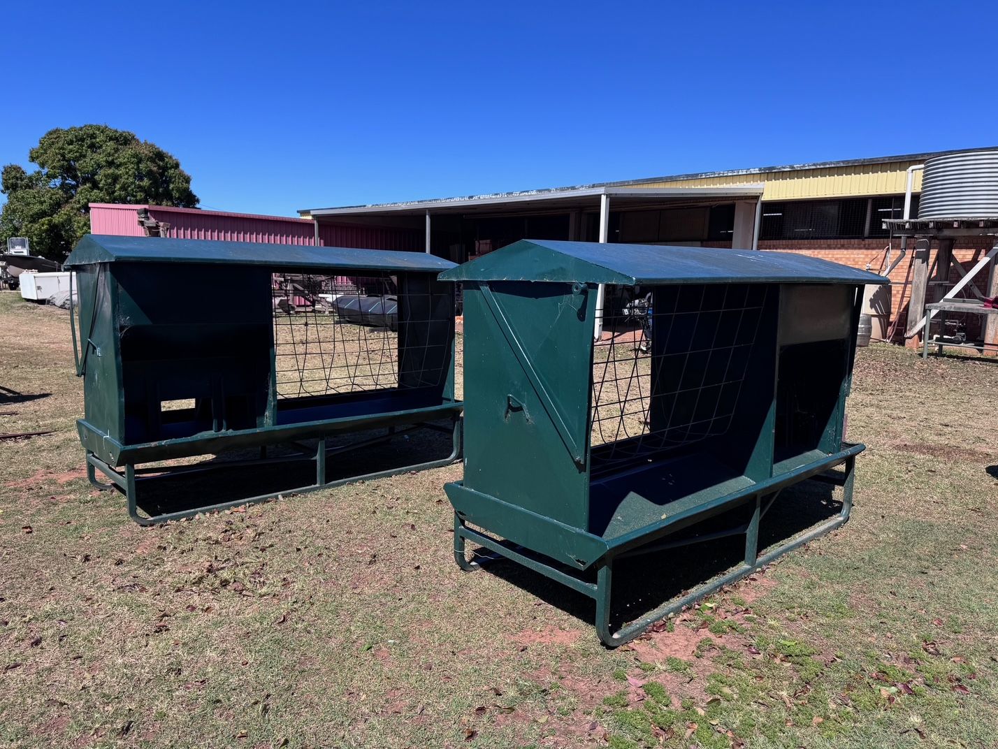 Two Green Metal Hay Feeders with Roofs — Bundaberg Auction Centre in Gooburrum, QLD