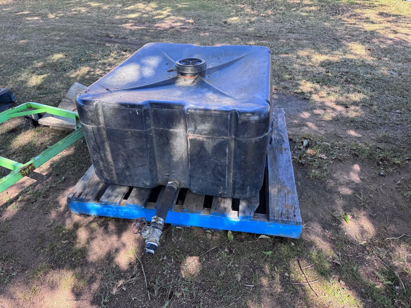 Black Water Tank on A Blue Wooden Pallet Outdoors — Bundaberg Auction Centre in Gooburrum, QLD