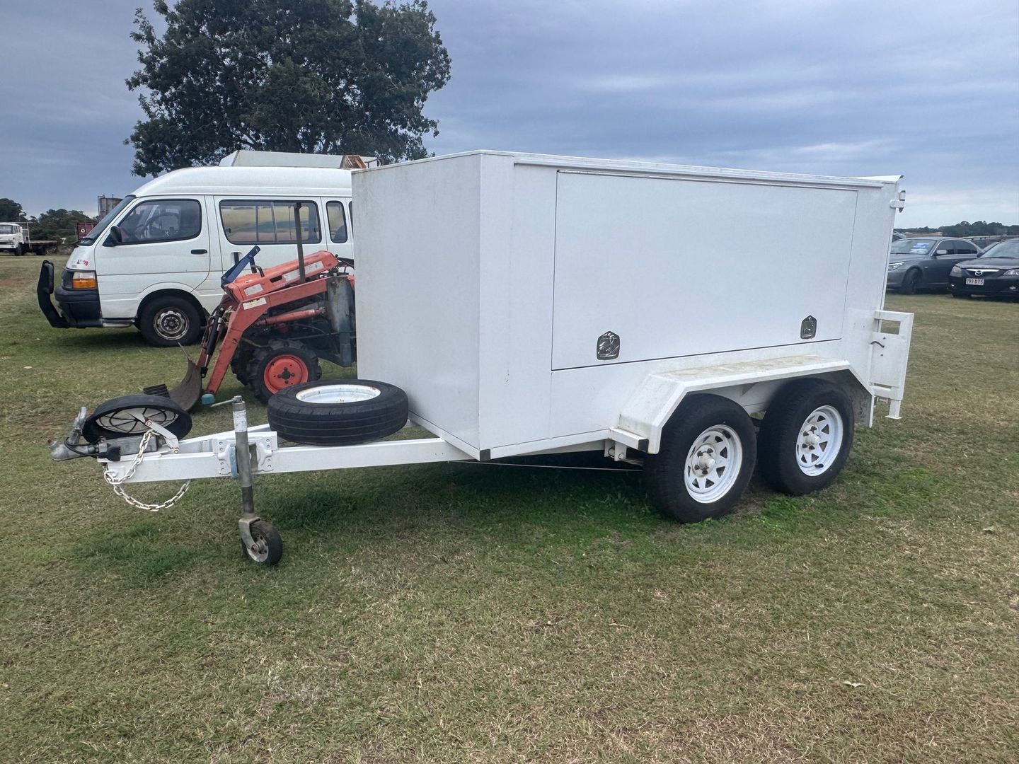 White Enclosed Utility Trailer Parked on Grass — Bundaberg Auction Centre in Gooburrum, QLD