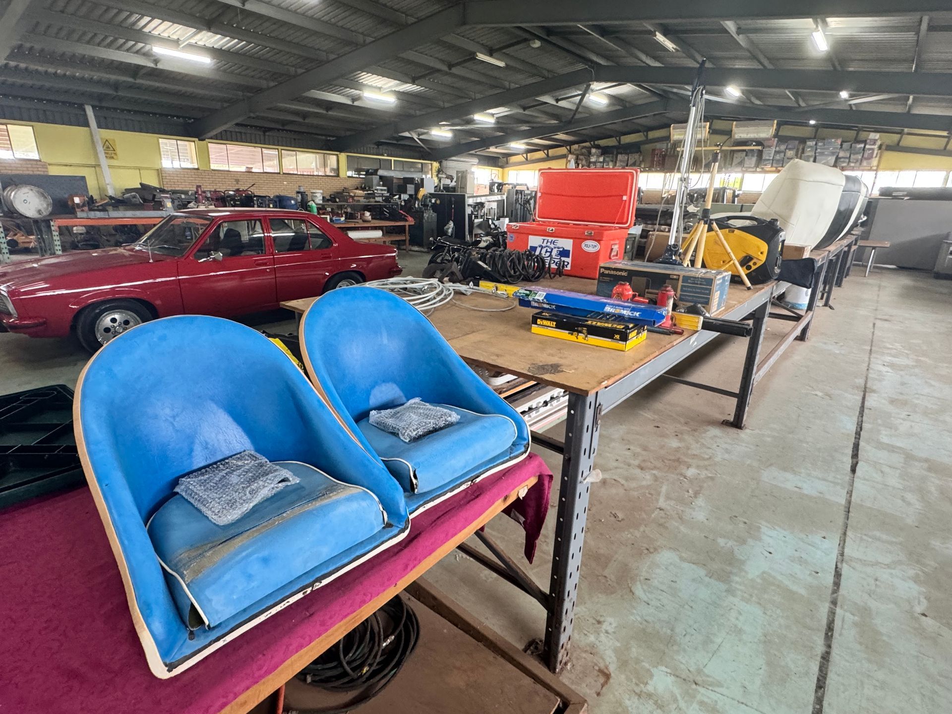 Two Blue Boat Seats on A Table Inside a Workshop, with Tools and A Red Car in The Background — Bundaberg Auction Centre in Gooburrum, QLD