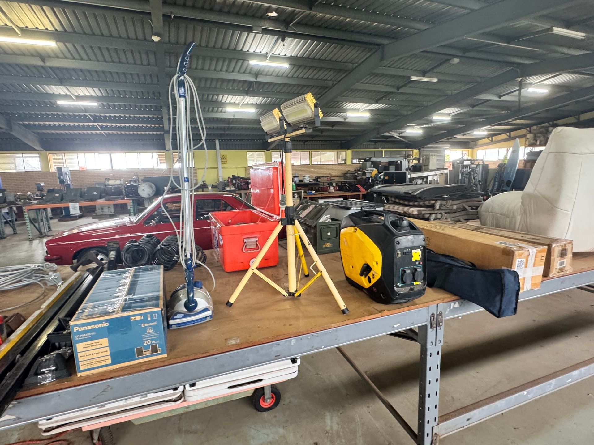 Warehouse Scene with Tools, a Red Car, and Equipment on A Table; Overhead Lighting — Bundaberg Auction Centre in Gooburrum, QLD