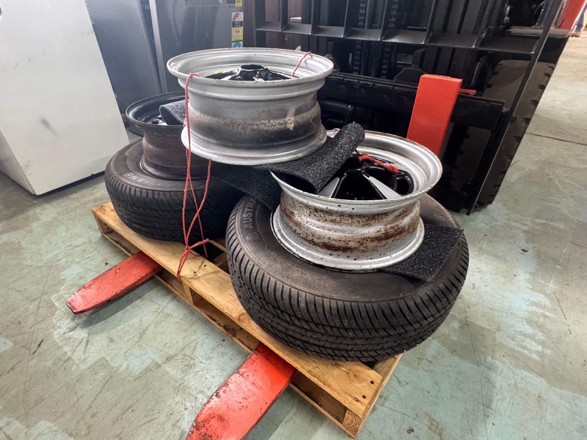 Tires and Rims Stacked on A Pallet with A Forklift in The Background — Bundaberg Auction Centre in Gooburrum, QLD