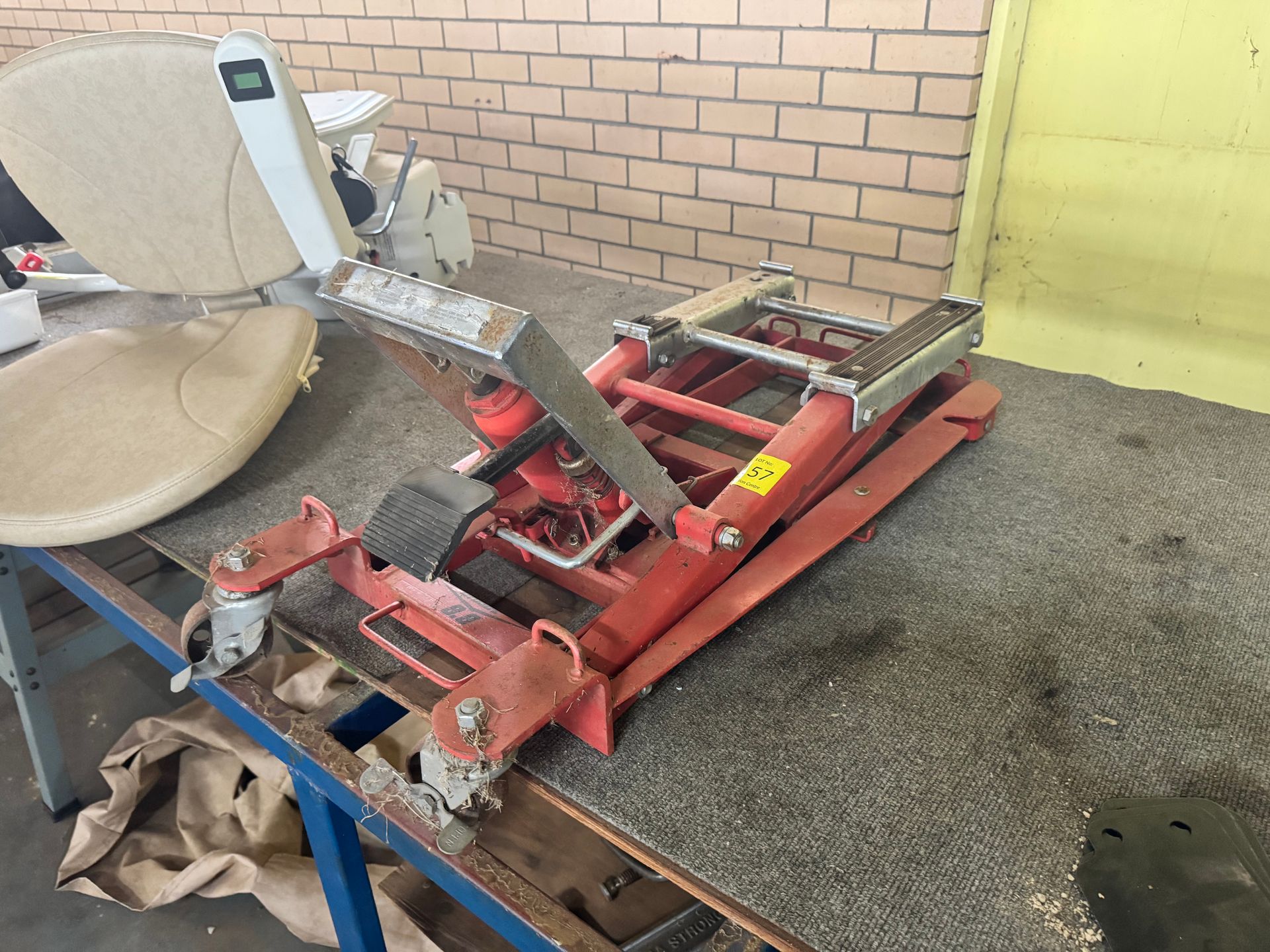Red and Silver Industrial Lift on A Workshop Table Near a Beige Chair — Bundaberg Auction Centre in Gooburrum, QLD