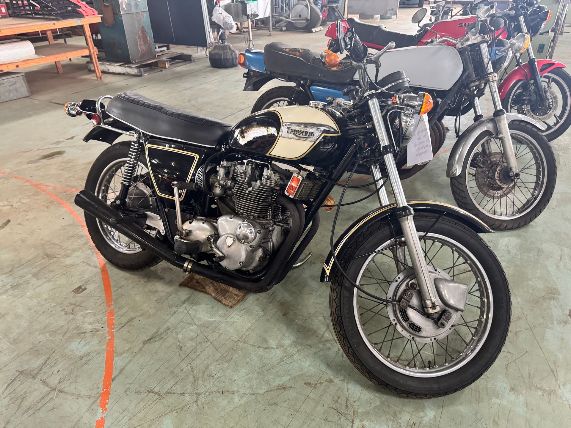 Black and Cream Vintage Motorcycle in A Shop, with Two Other Bikes Behind It — Bundaberg Auction Centre in Gooburrum, QLD