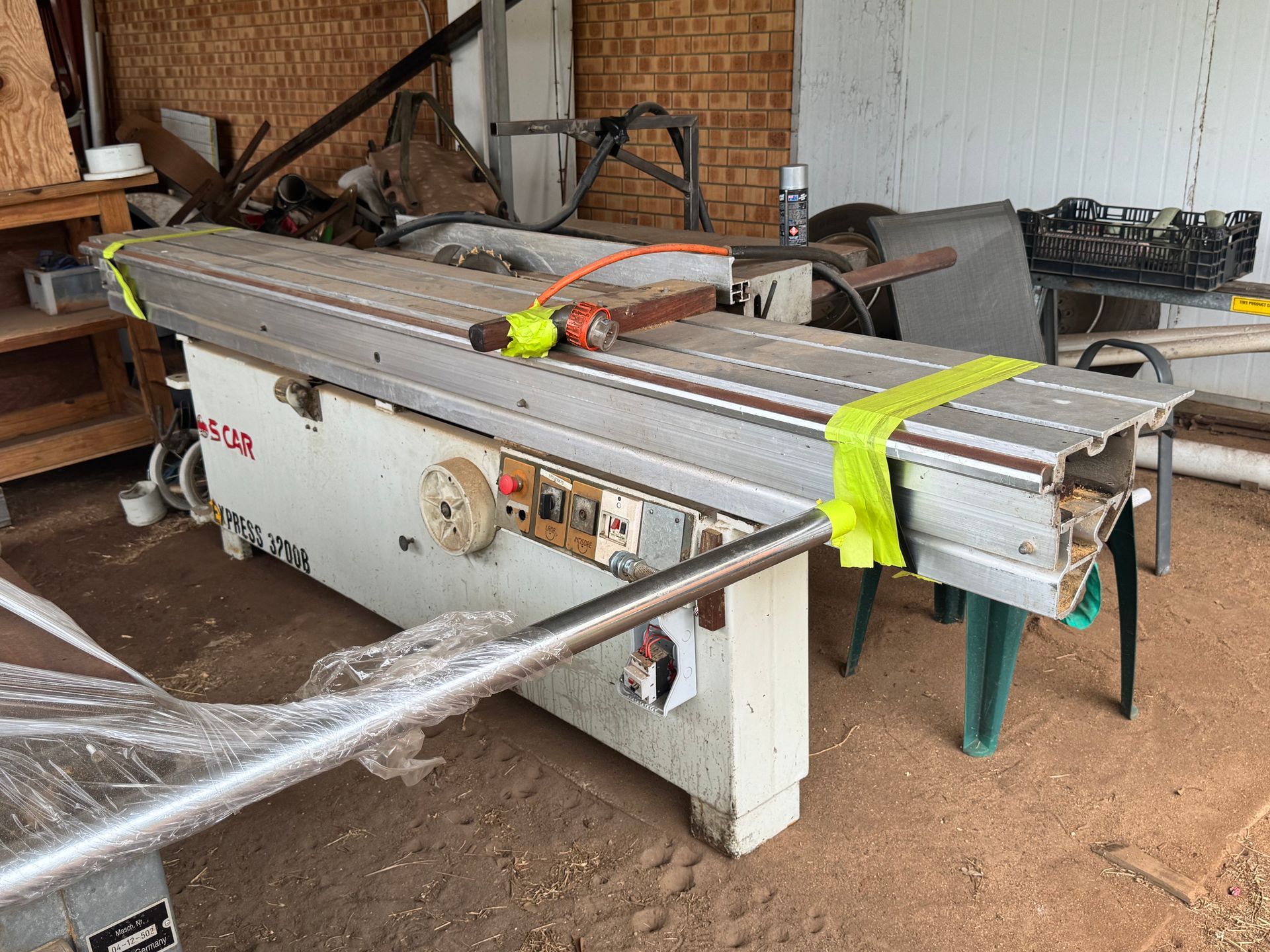 Industrial Woodworking Machine, White and Silver, Strapped with Yellow Tape, in A Cluttered Workshop — Bundaberg Auction Centre in Gooburrum, QLD