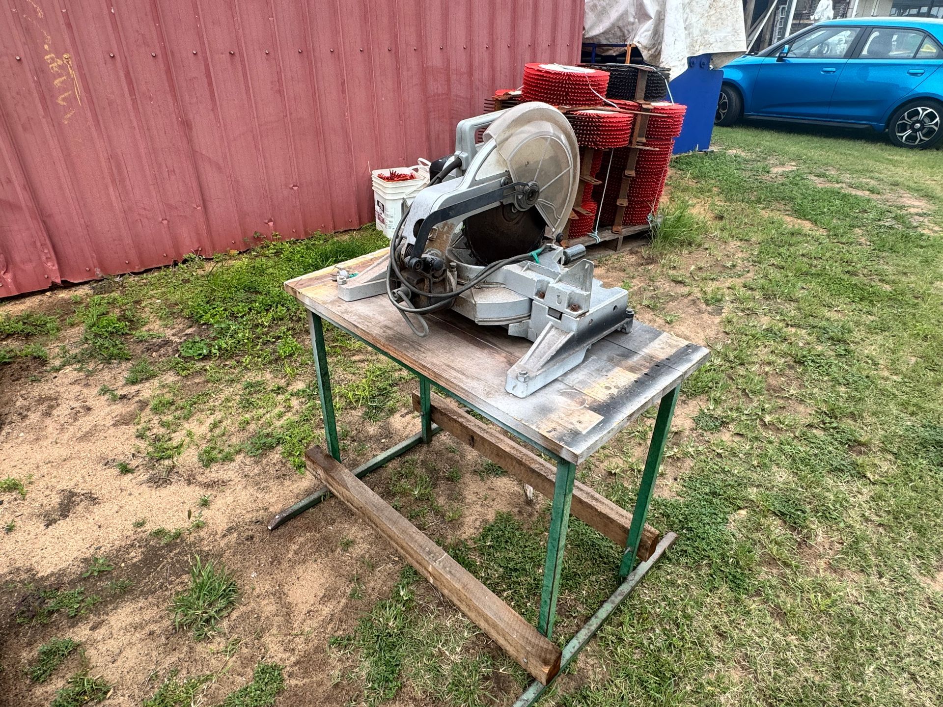 Mitre Saw on A Wooden Table, Outside Near a Red Building and A Blue Car — Bundaberg Auction Centre in Gooburrum, QLD