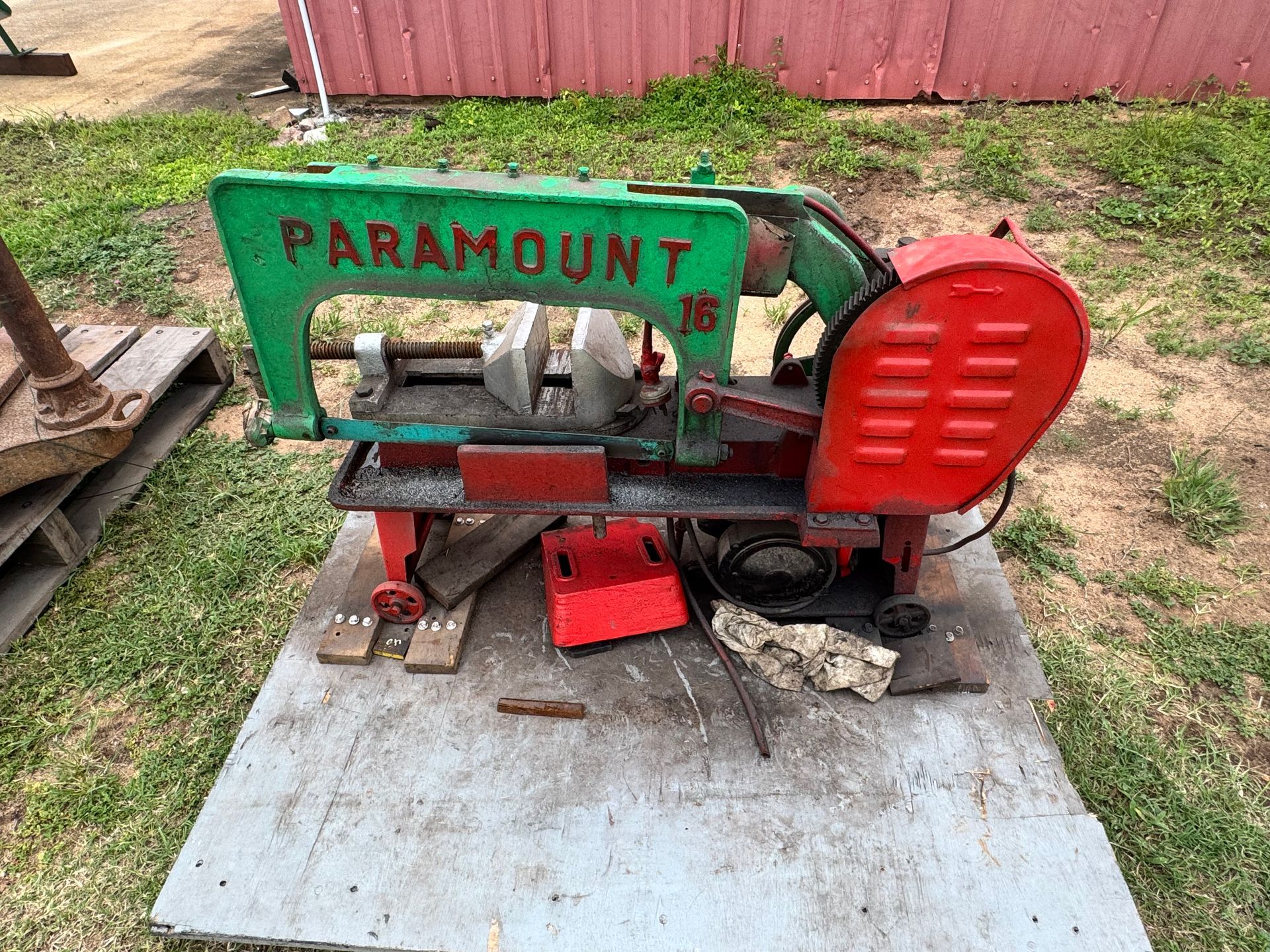 Paramount 16 Metal-Cutting Bandsaw, Green and Red, on A Gray Platform Outdoors — Bundaberg Auction Centre in Gooburrum, QLD