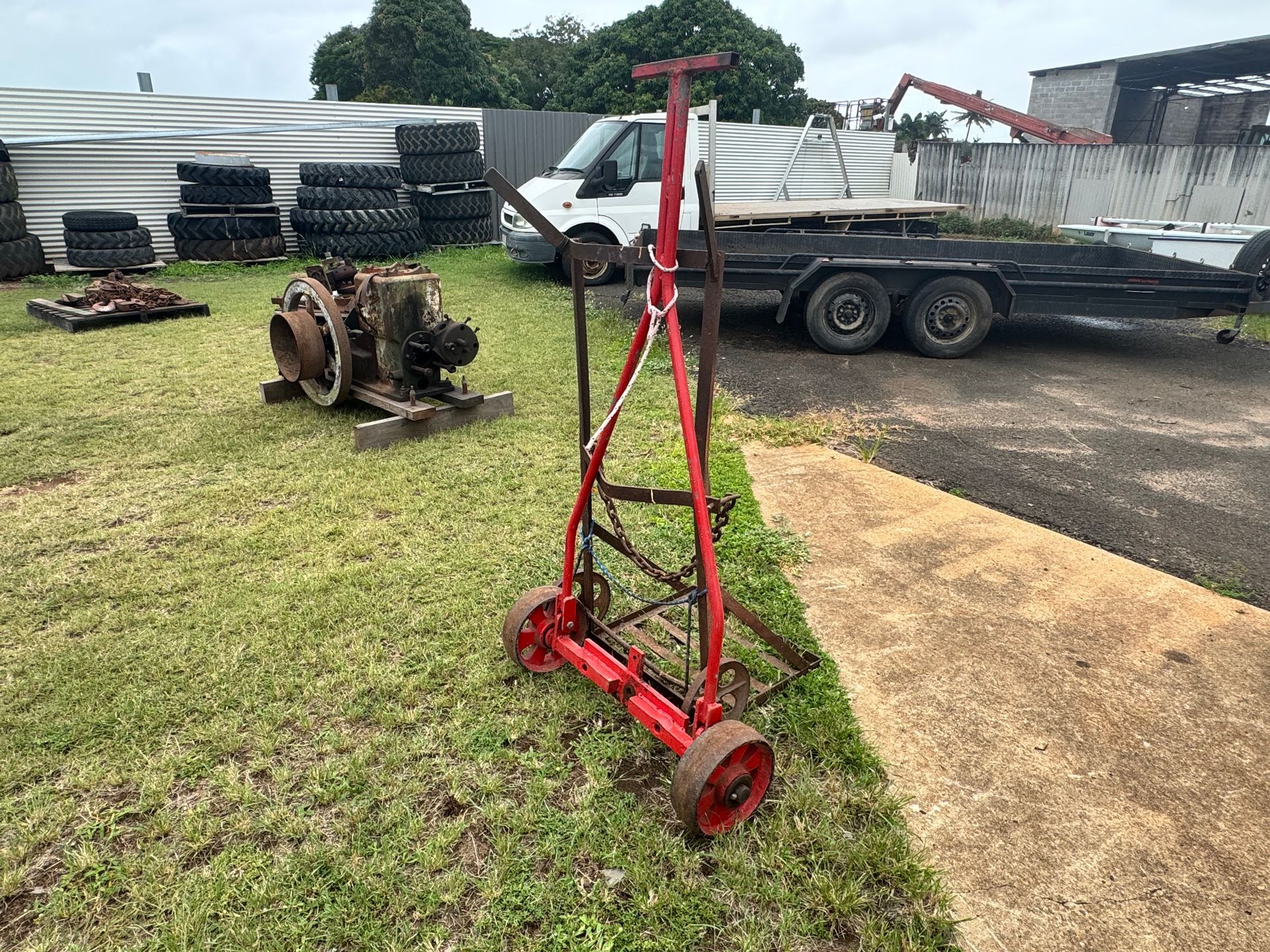 Red Metal Cart with Wheels on Grass, an Engine, and Trailer in Background — Bundaberg Auction Centre in Gooburrum, QLD
