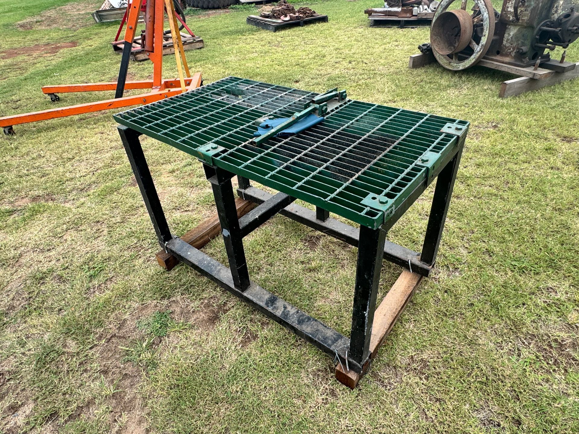 Green-Topped Work Table with A Saw on Black Legs, on Grass, Outdoors — Bundaberg Auction Centre in Gooburrum, QLD