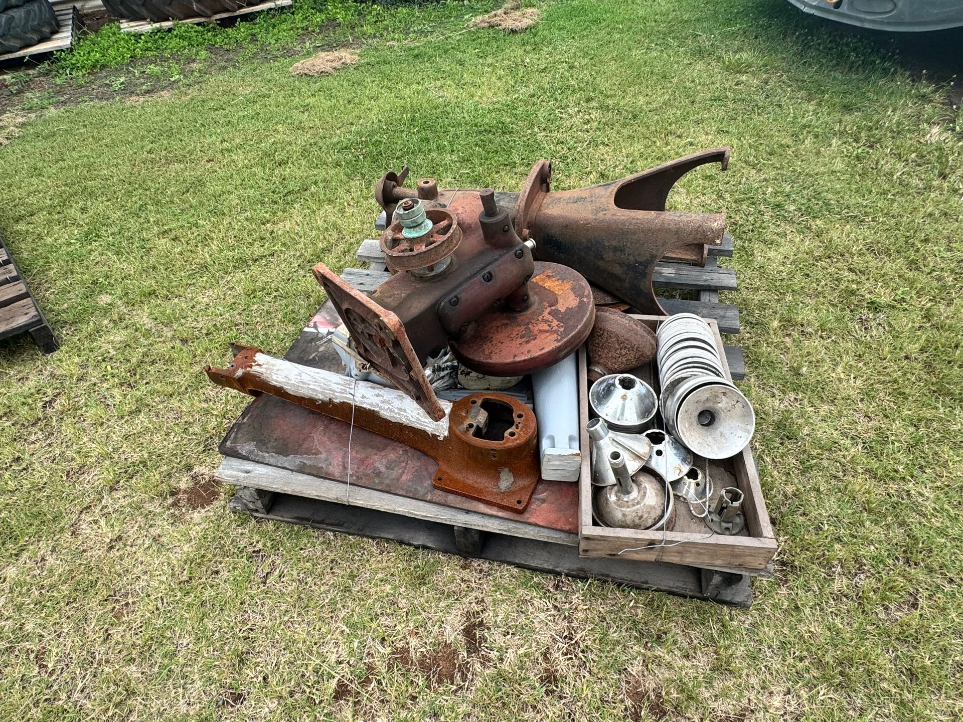 Rusty Metal Machine Parts Scattered on A Wooden Pallet Outdoors on Green Grass — Bundaberg Auction Centre in Gooburrum, QLD