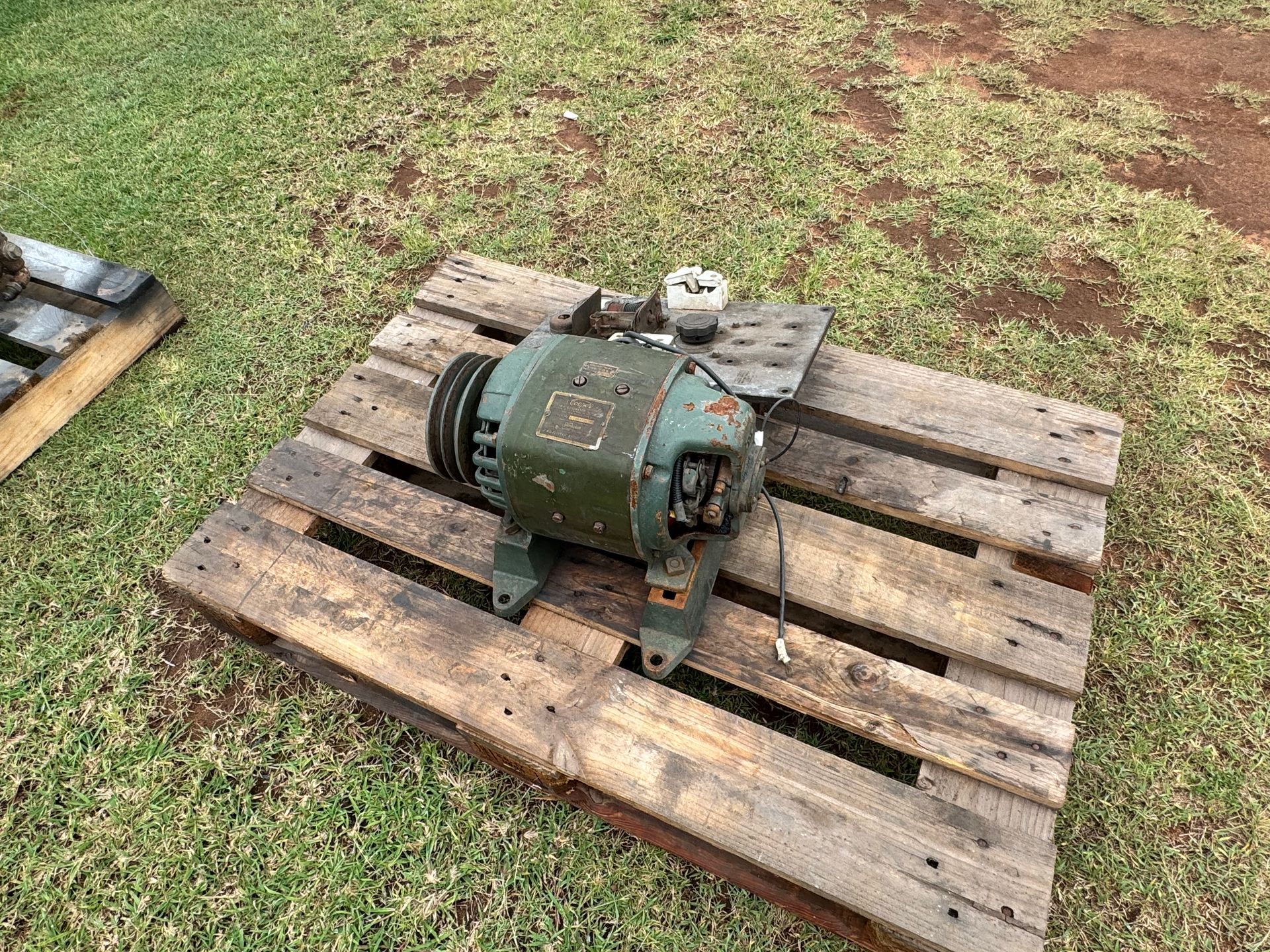 Electric Motor on A Wooden Pallet, Outdoors on Grass — Bundaberg Auction Centre in Gooburrum, QLD