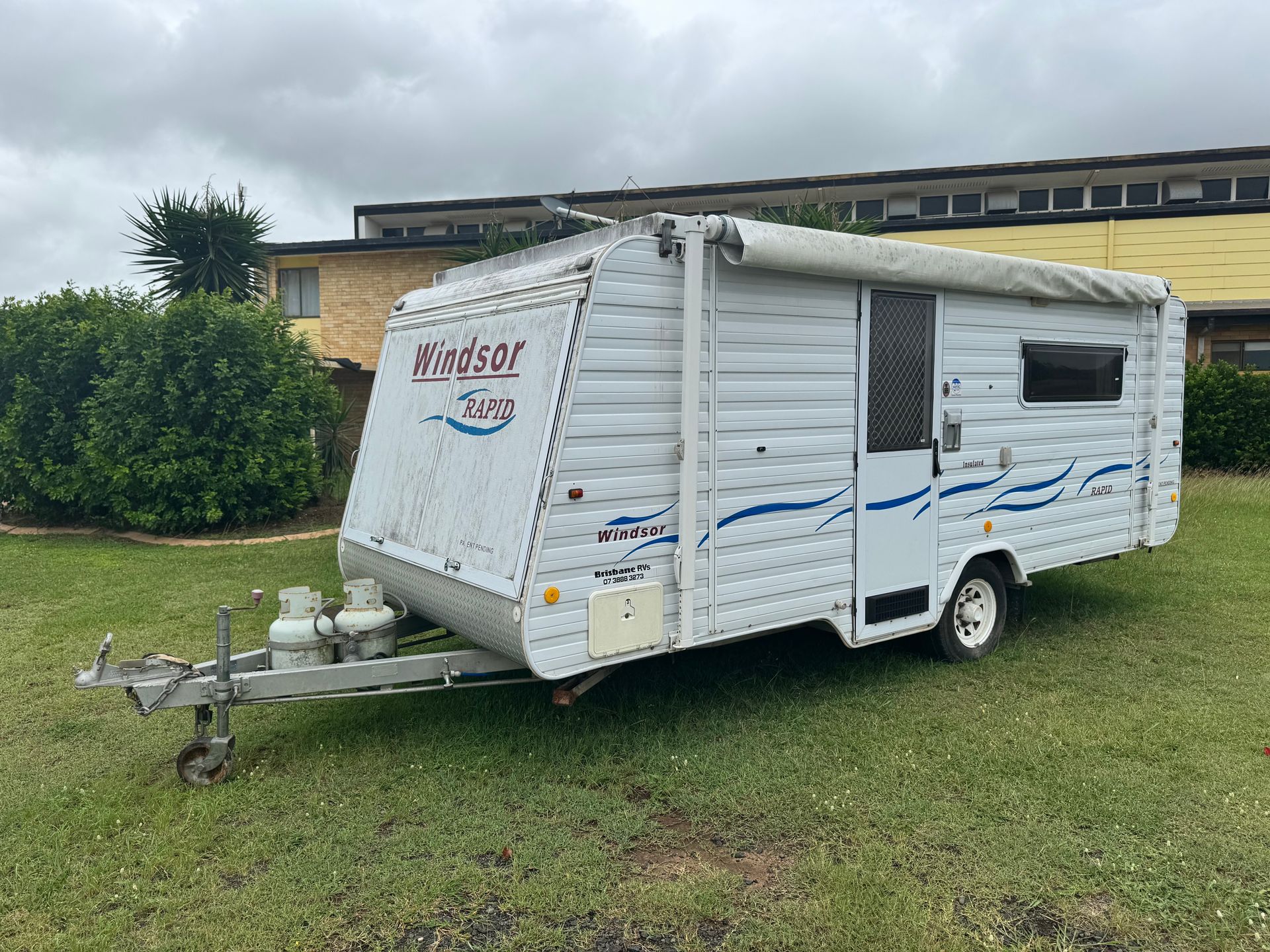 White Windsor Caravan on Grass, with Awning and Blue Accents, Parked Outdoors — Bundaberg Auction Centre in Gooburrum, QLD