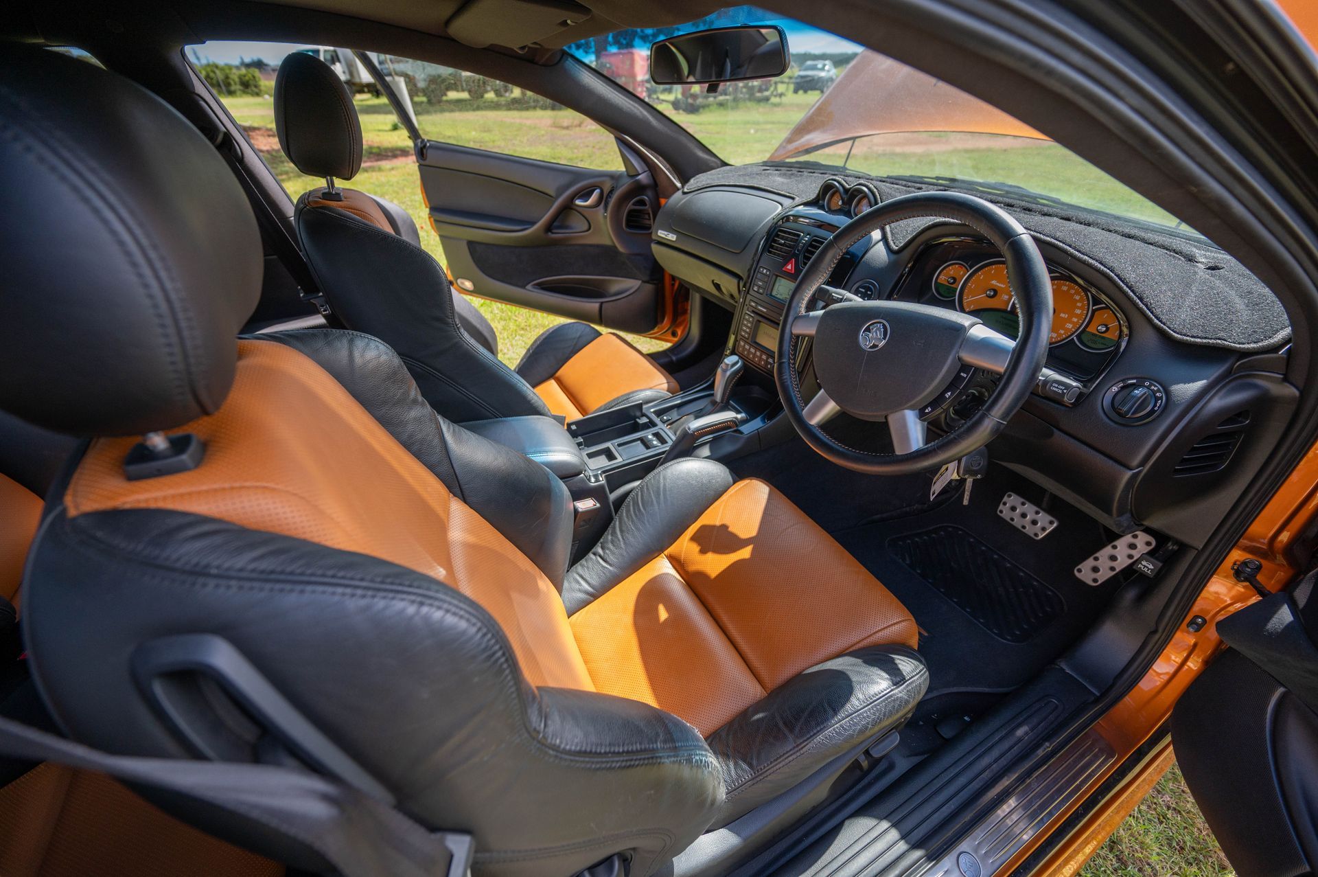 Orange and Black Car Interior with Leather Seats, Steering Wheel, and Open Door — Bundaberg Auction Centre in Gooburrum, QLD