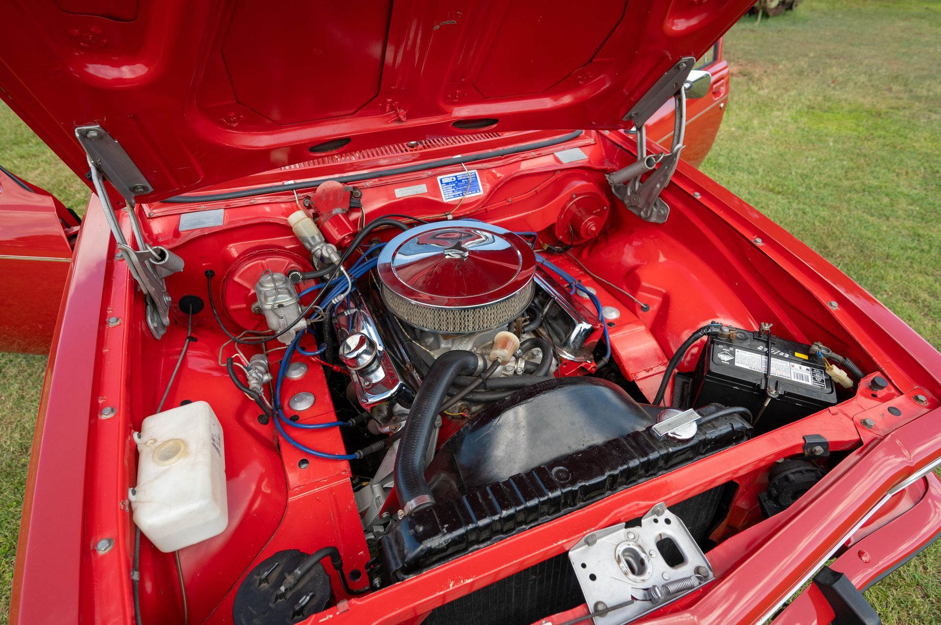 Red Car Engine Bay with Chrome Details, Black Fan, Battery, and Fluid Reservoir — Bundaberg Auction Centre in Gooburrum, QLD