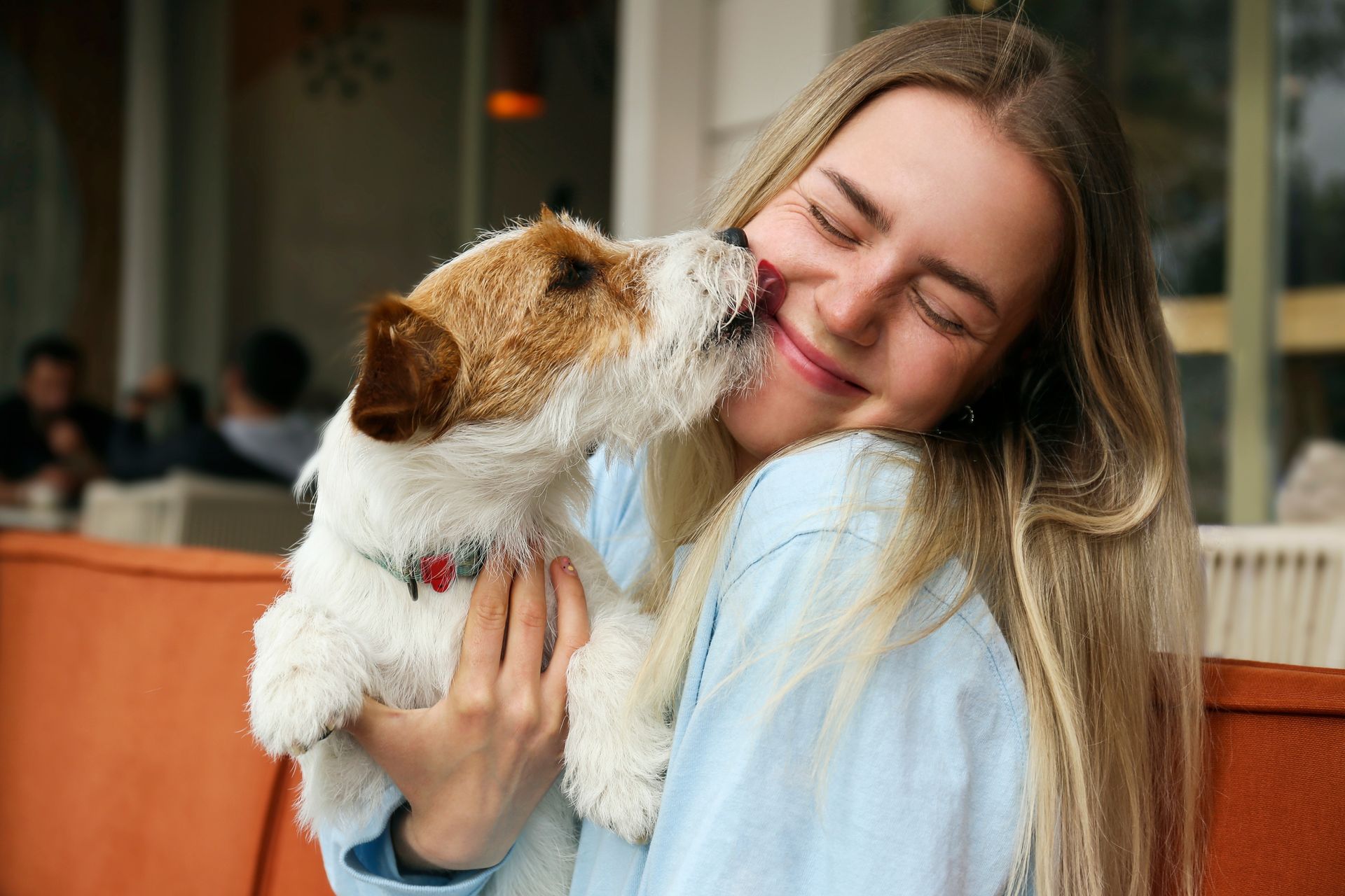 A woman is holding a dog in her arms and the dog is sniffing her face.