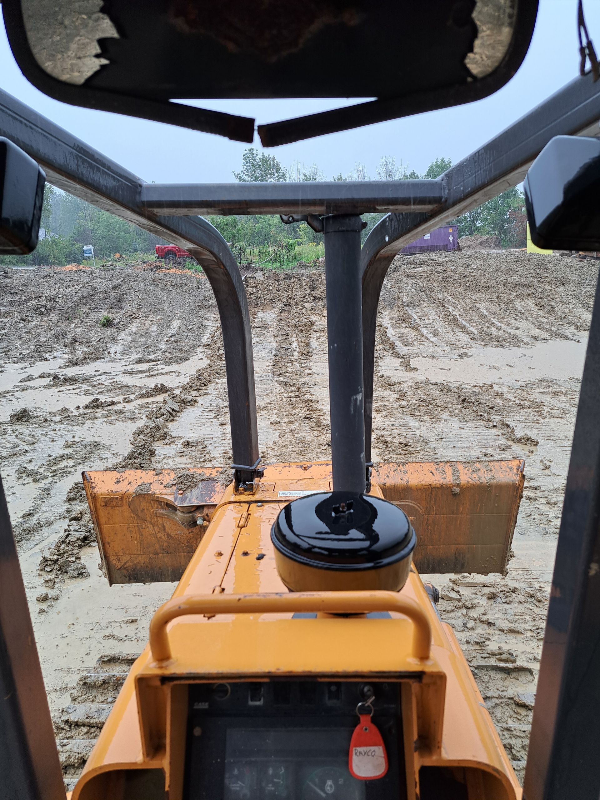 View from inside a yellow bulldozer, operating in muddy terrain.