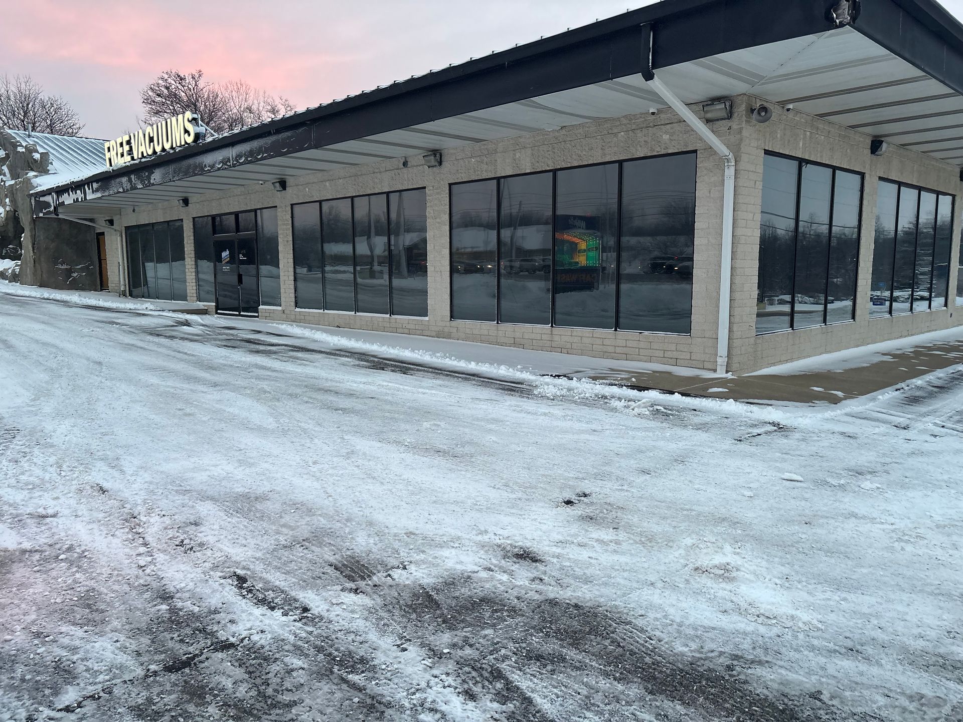 Exterior of a business building with large windows, covered in snow; overcast sky.