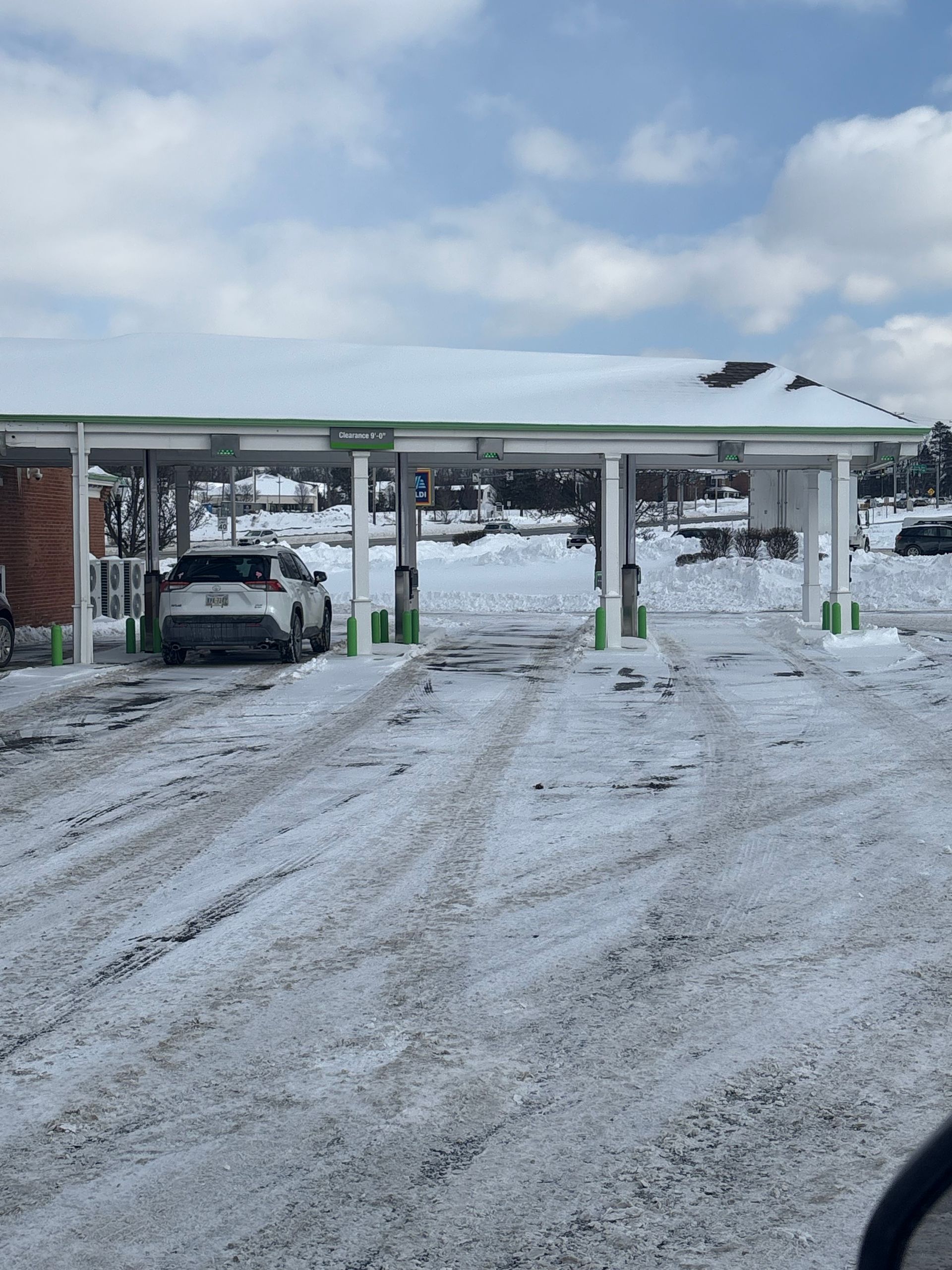 Car at a car wash under a snow-covered canopy. Winter scene with snowy ground.