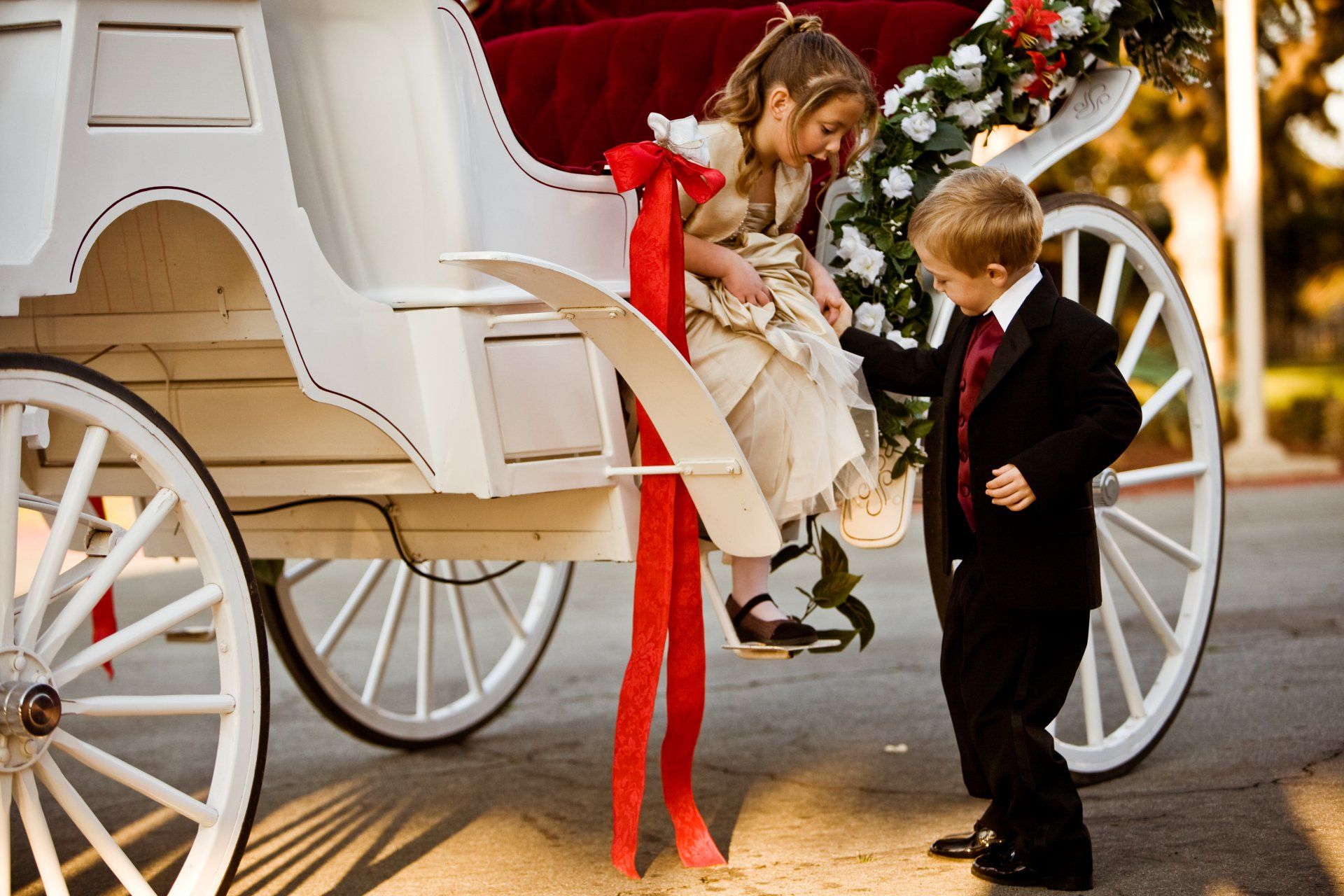 groomsmen helping flower girl out of a horse carriage, kids with horse carriage at a wedding