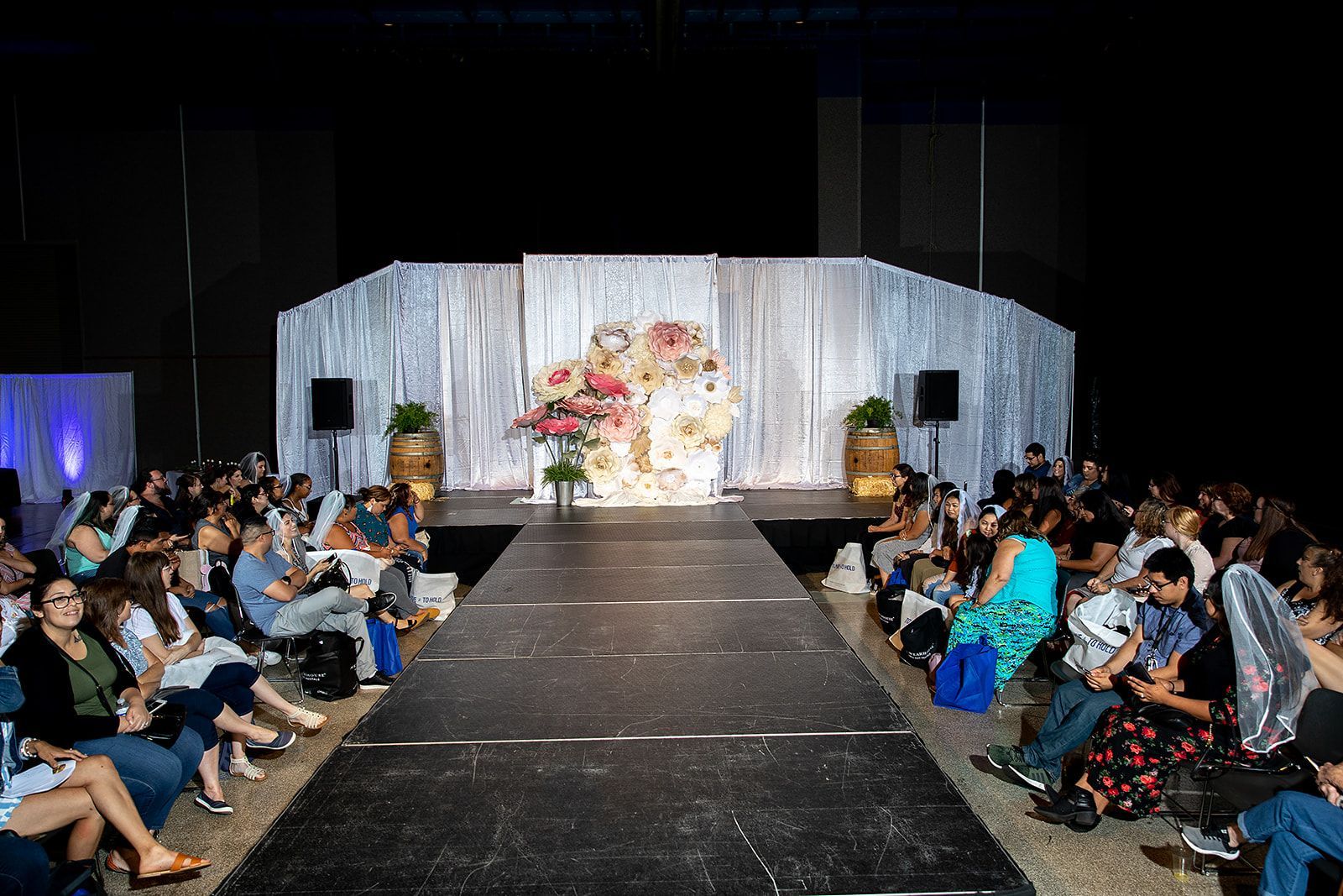 A group of people are sitting in front of a runway at a fashion show.