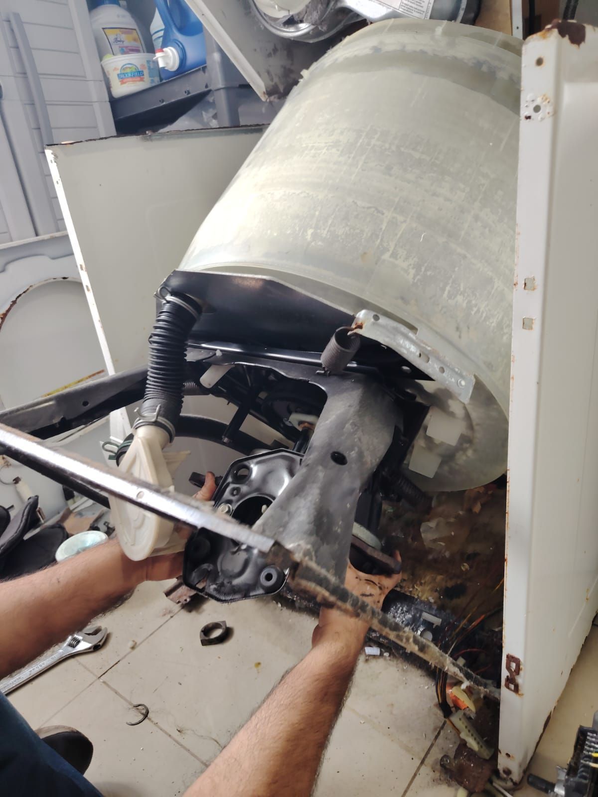 Persona utilizando un destornillador en la puerta de una lavadora.