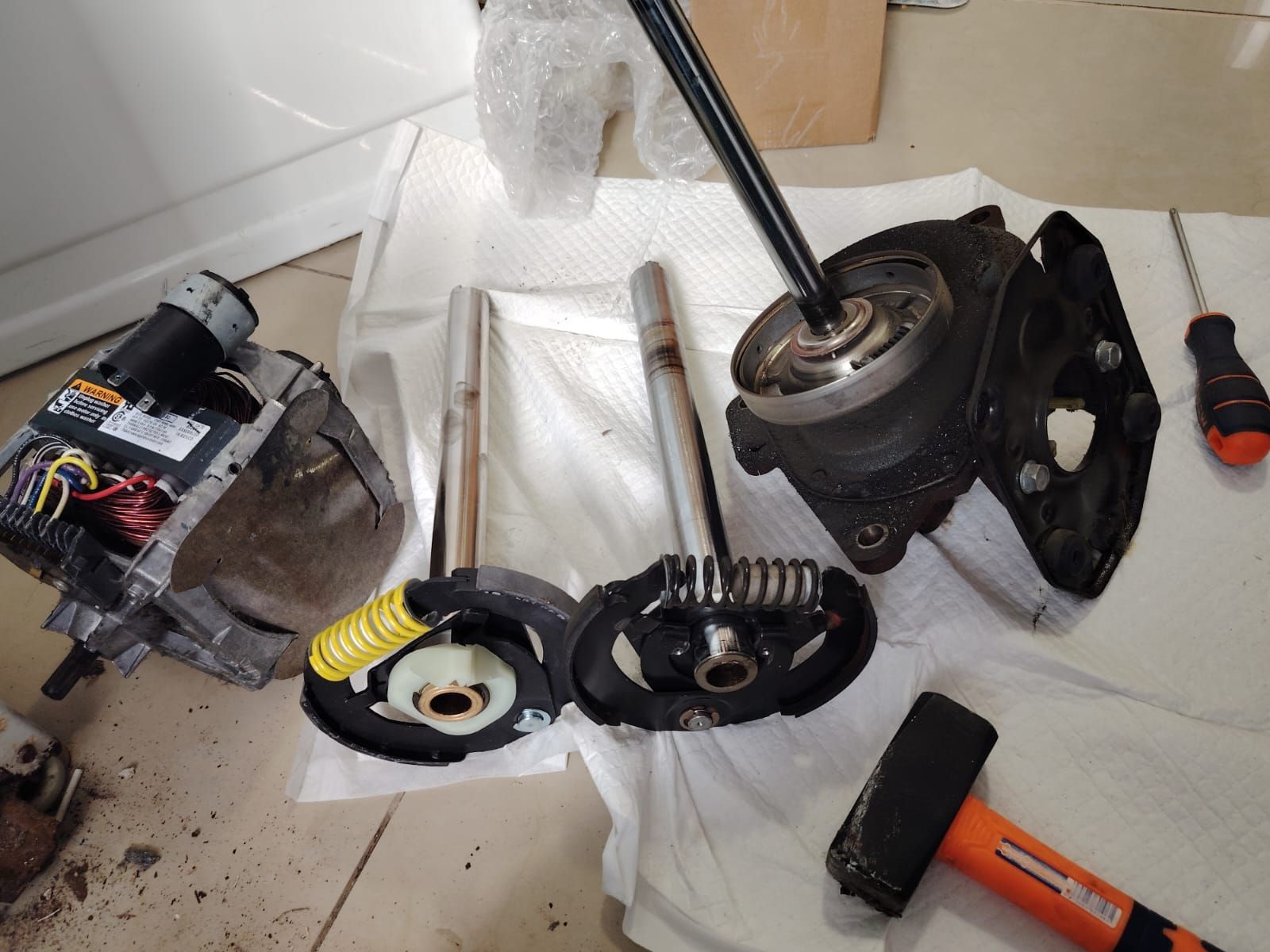 Persona con guantes rojos reparando una lavadora, puerta abierta, bandeja de detergente retirada.