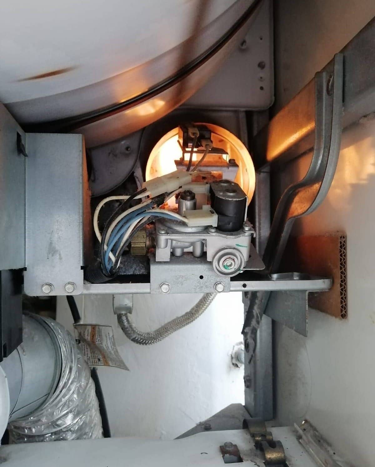 Persona repara una lavadora con un destornillador.