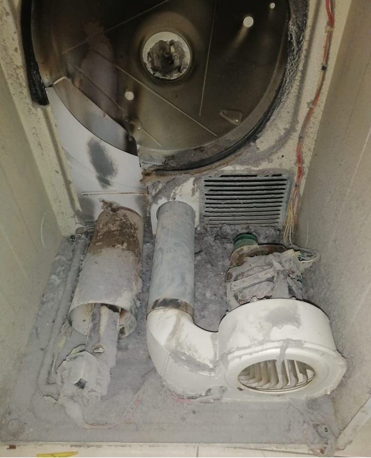 Un técnico de reparaciones utiliza un multímetro en una lavadora abierta, en el interior.