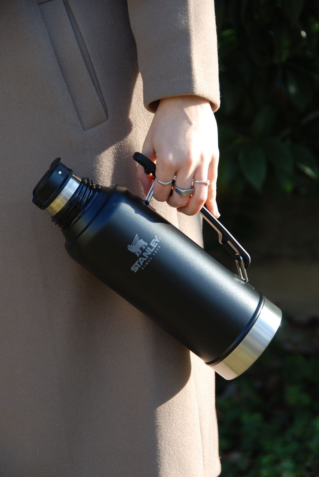 Un frasco de perfume está sobre una cama al lado de una caja.