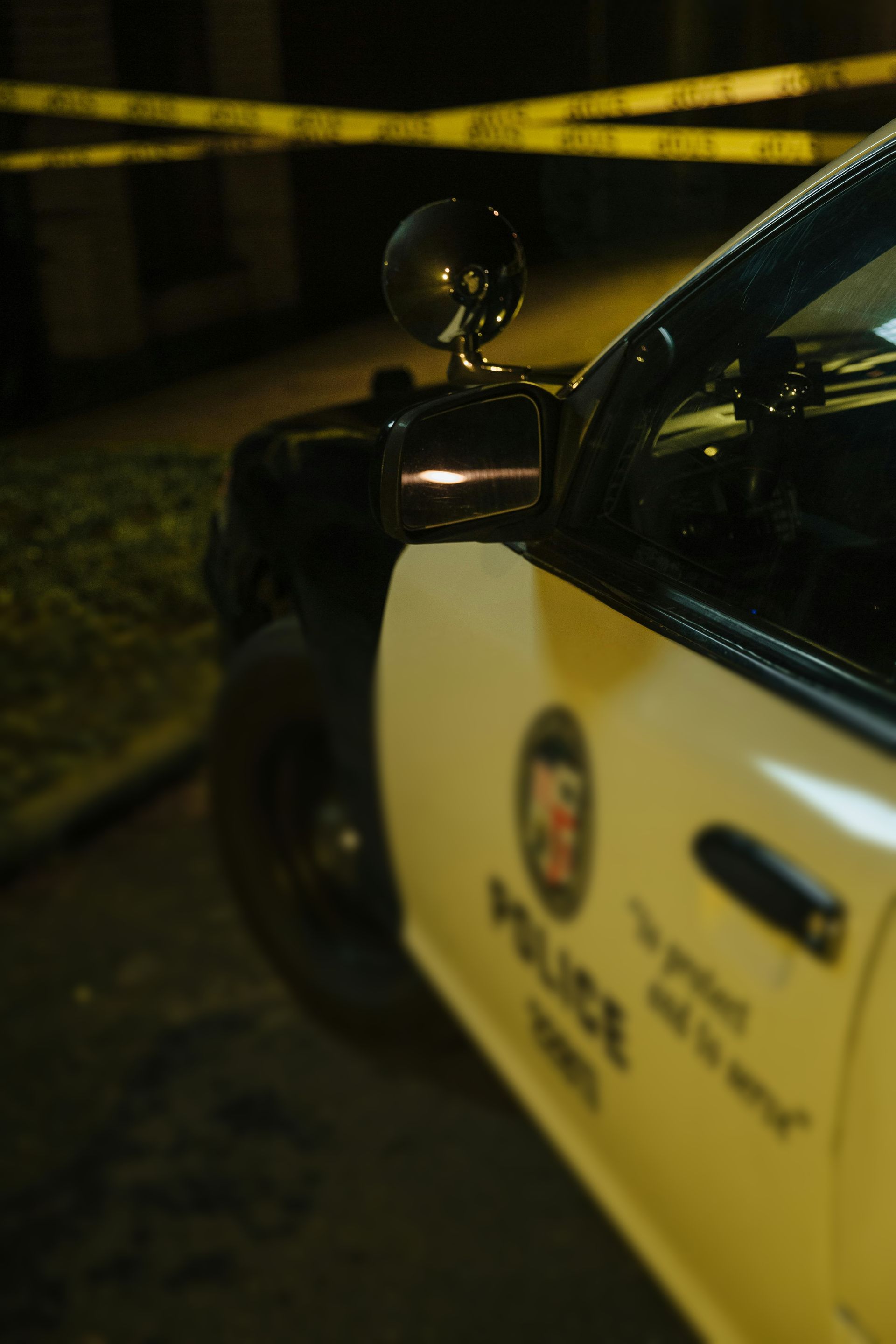 A police car is parked in front of a yellow tape