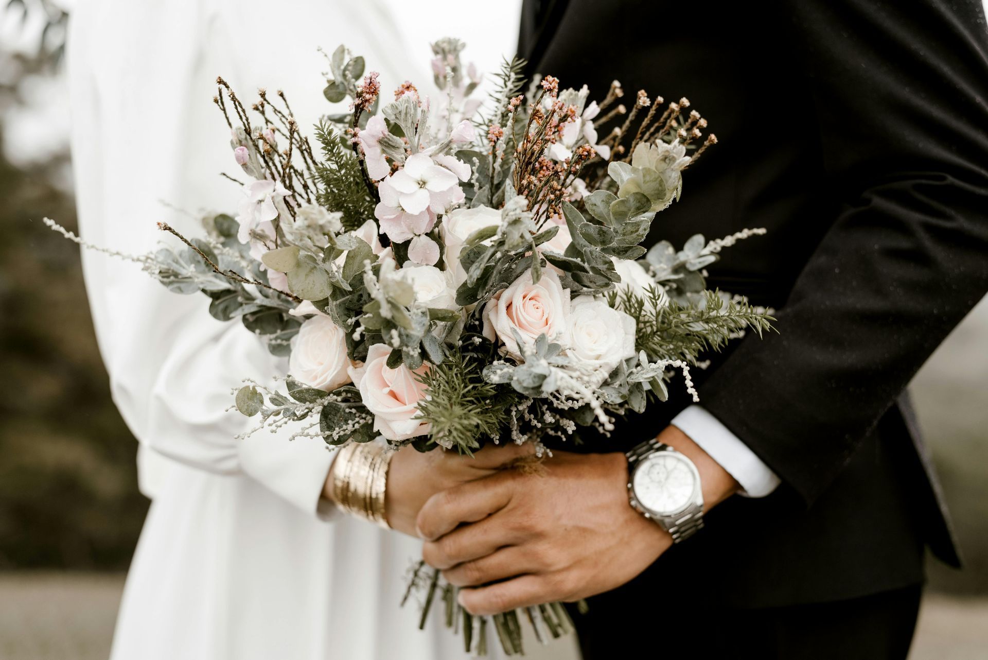 A bride and groom are holding a bouquet of flowers.