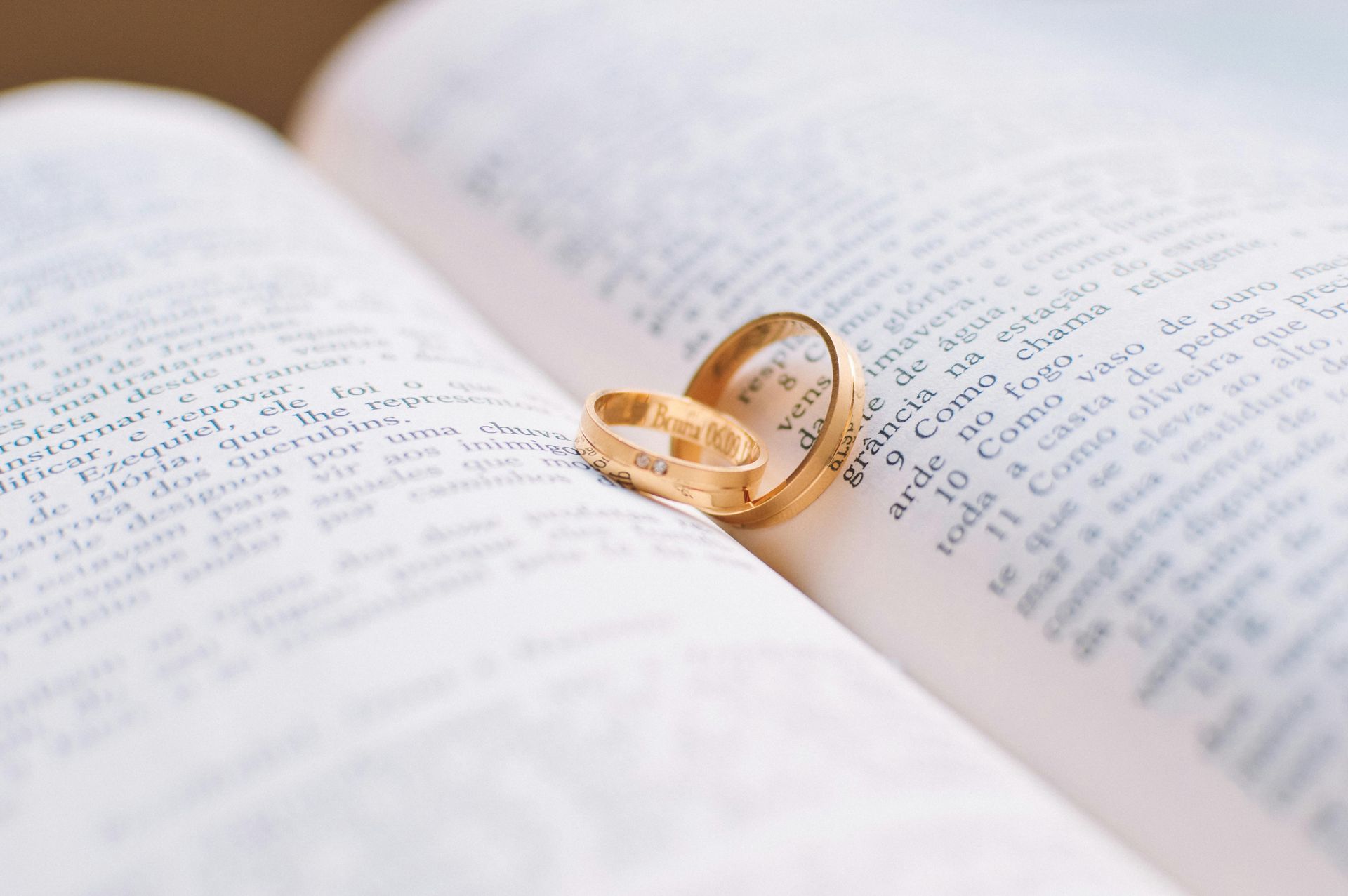 Two wedding rings are sitting on top of an open book.