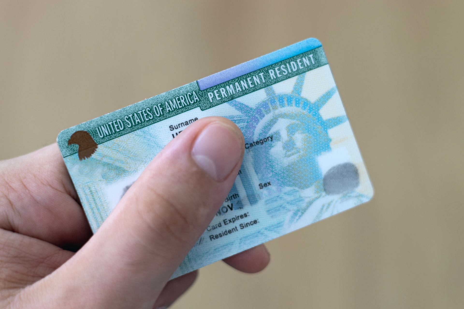 A person is holding a green card with the statue of liberty on it.