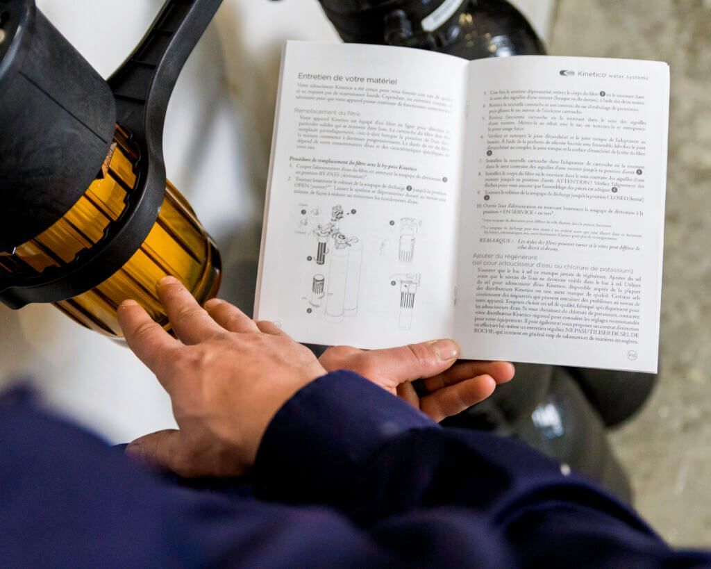 Person in a blue shirt reads a manual next to a black and yellow machine in an indoor setting.