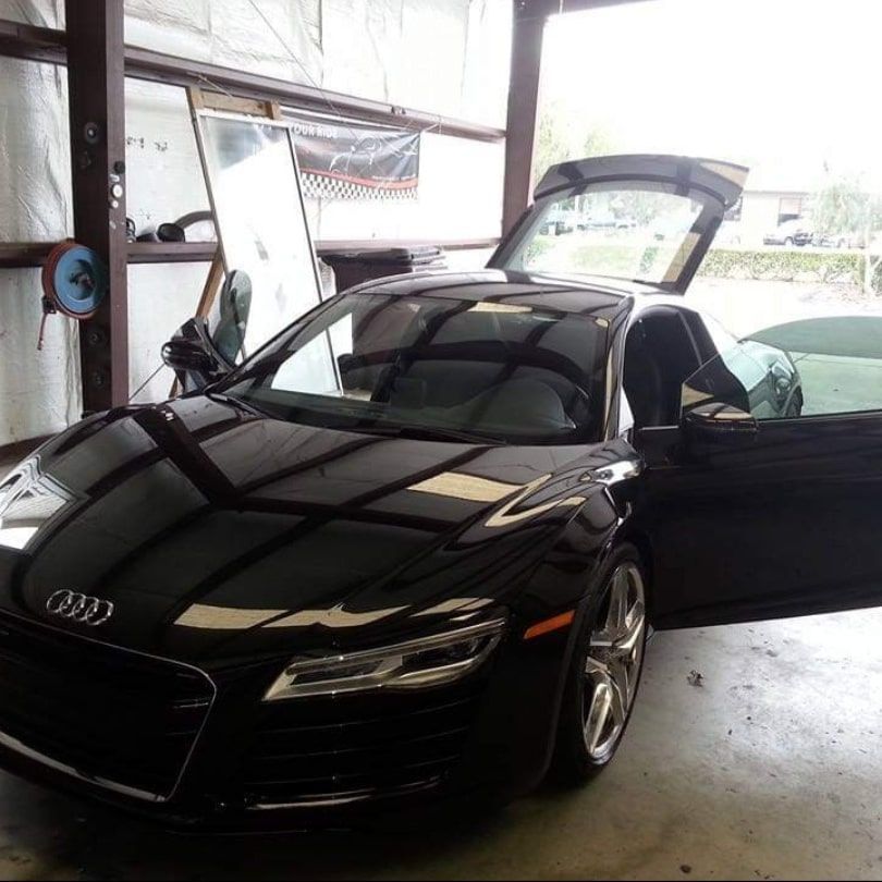 A black audi is parked in a garage with its door open