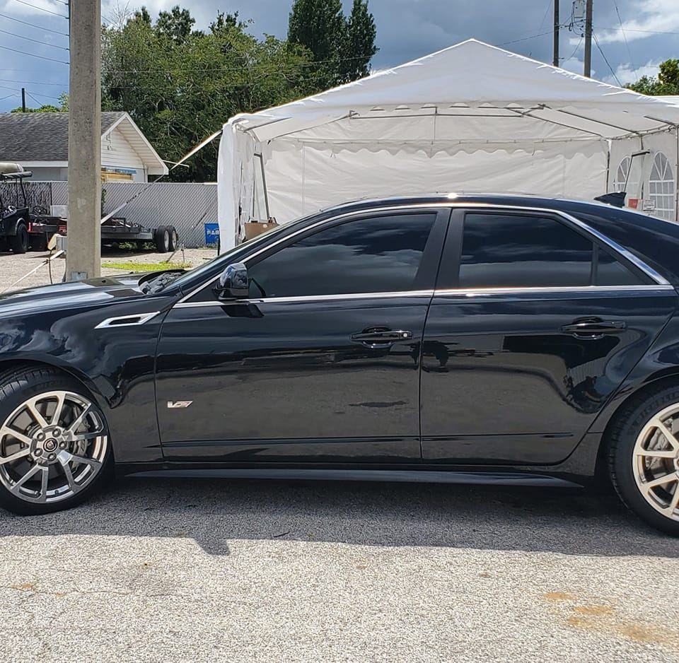 A black car is parked in front of a white tent