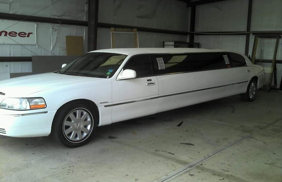 A white limousine is parked in a garage next to a sign that says pioneer