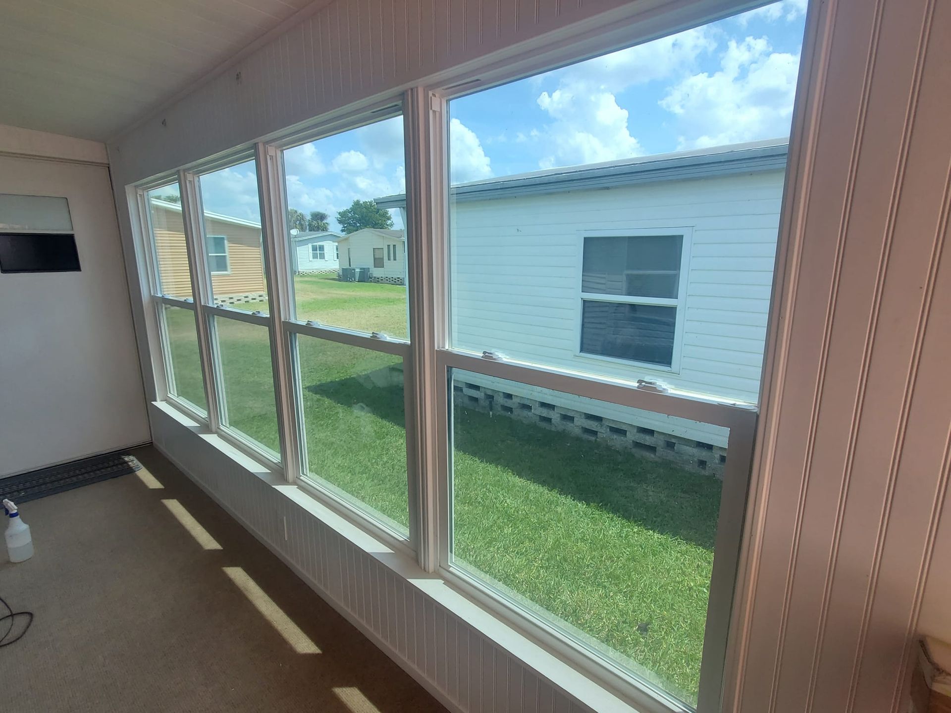 A room with a lot of windows and a view of a mobile home.