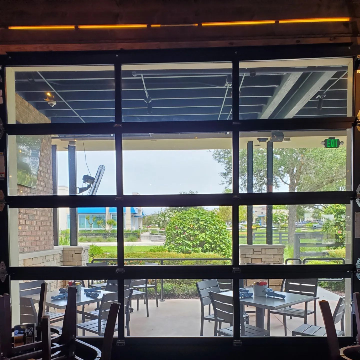 A large window with a view of a patio with tables and chairs.