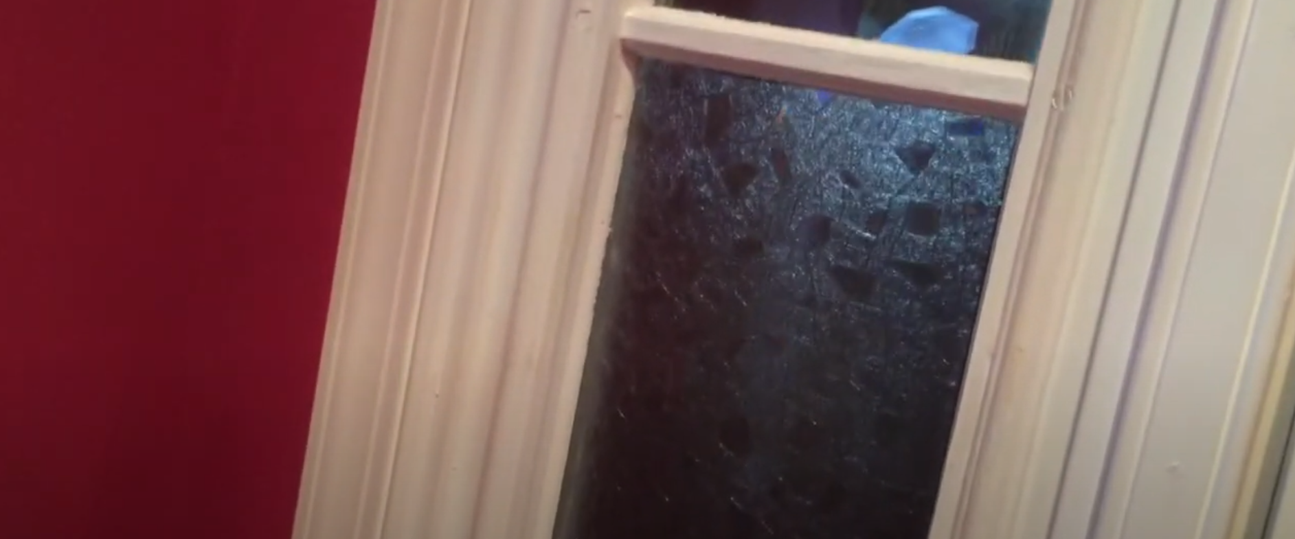 A close up of a window with a red wall in the background.