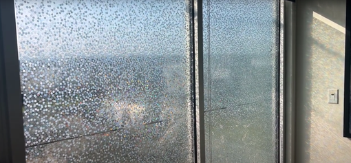 A room with a sliding glass door and a view of the ocean.