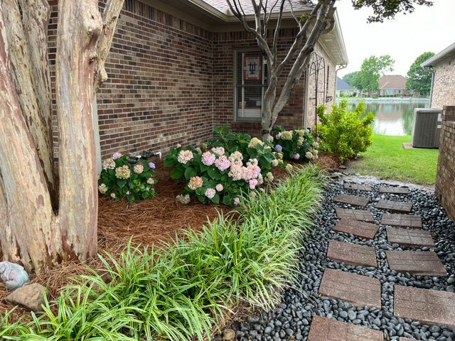 A brick house with a walkway leading to it and flowers in front of it