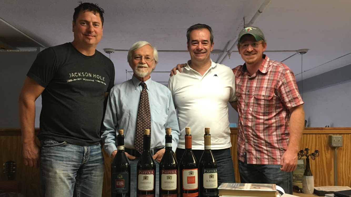 A group of men are standing next to each other holding bottles of wine.