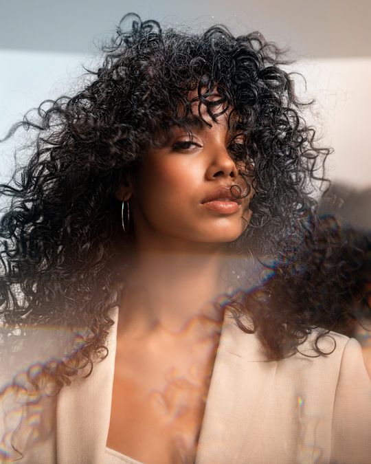 Woman With A Beautiful Curly Hair Standing In Front Of A Mirror — Siddha Hair Studio in Currajong, QLD