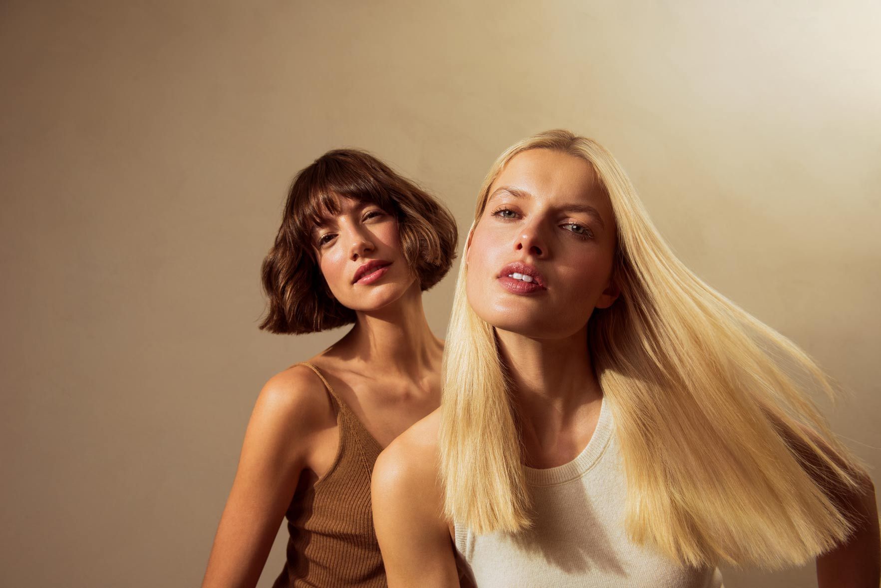 Two Women Standing Next To Each Other With Their Hair Blowing — Siddha Hair Studio in Currajong, QLD