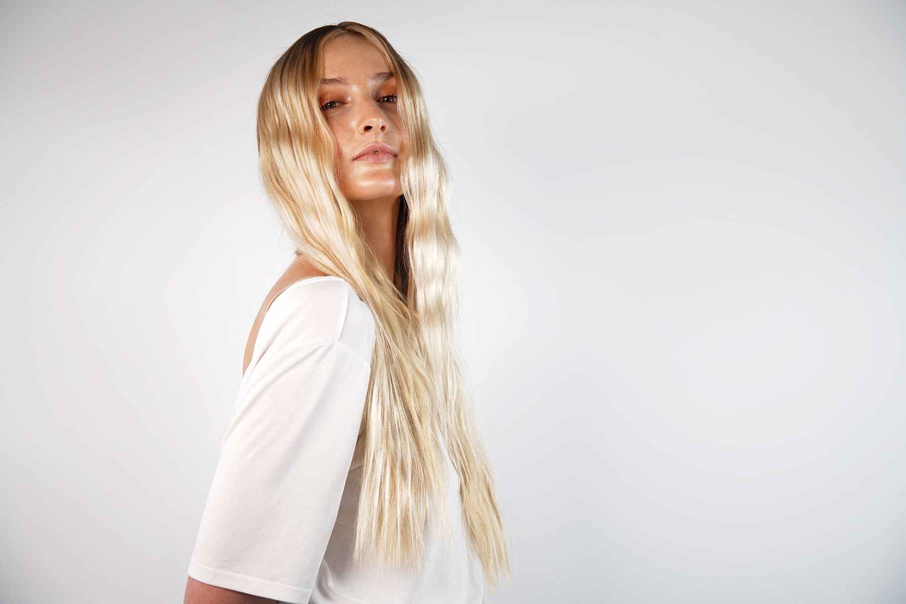 Woman With Long Blonde Hair Is Wearing A White Shirt — Siddha Hair Studio in Currajong, QLD