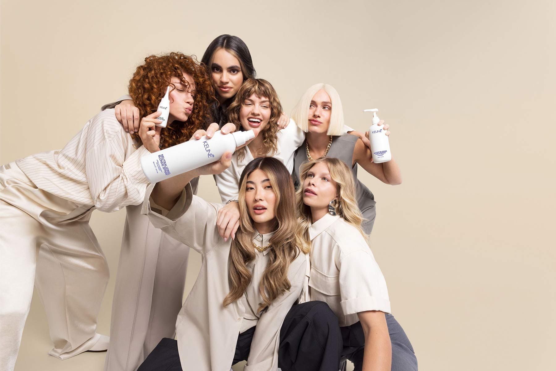 Group Of Women Are Posing For A Picture And One Of Them Is Holding A Bottle Of Shampoo — Siddha Hair Studio in Currajong, QLD