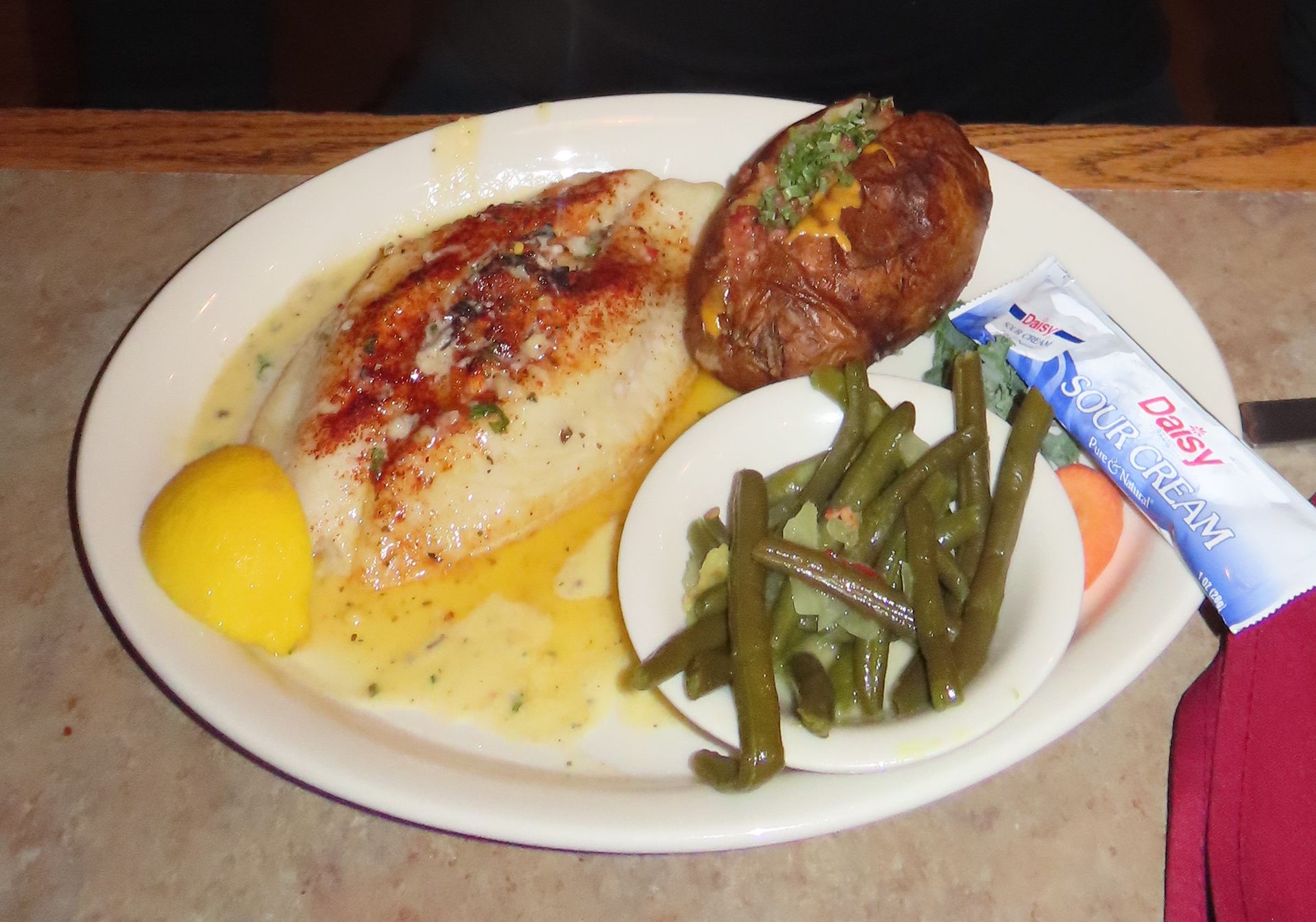 a plate of food with green beans and a potato on a table